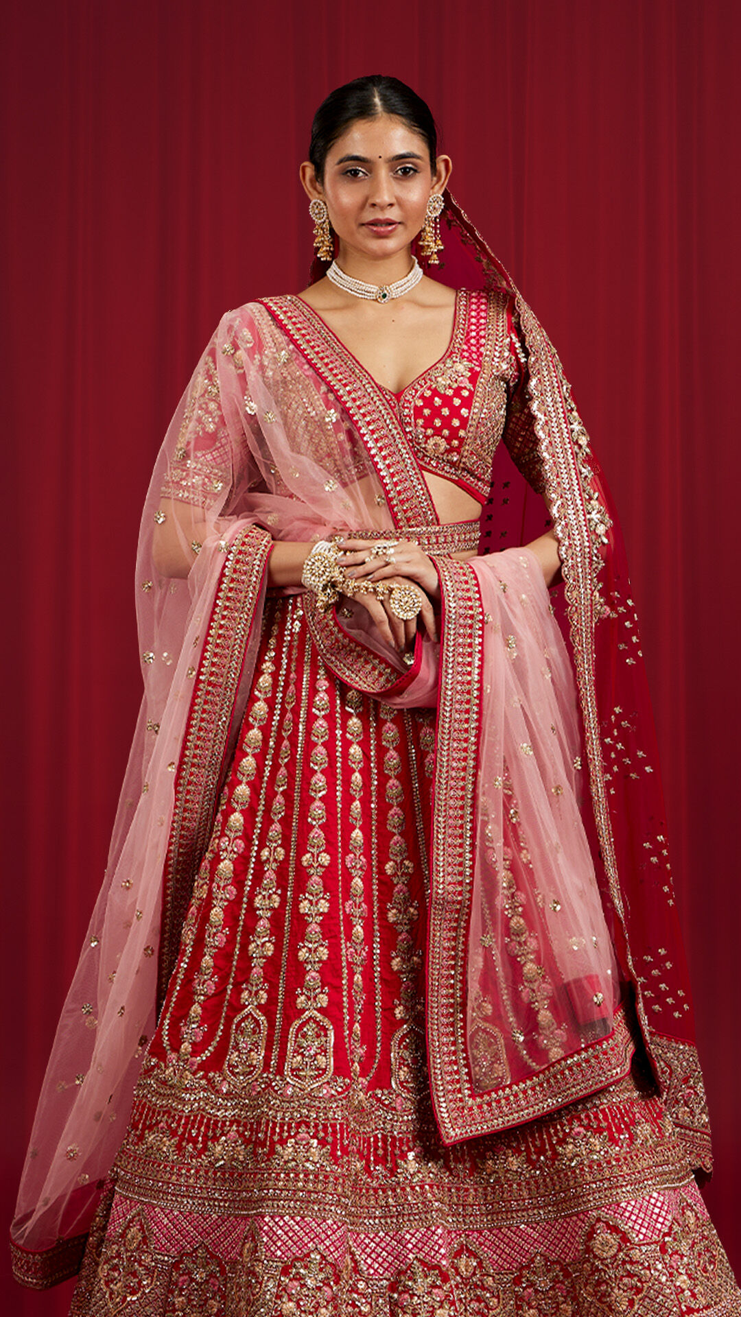A bride in beautifull red bridal lehenga with pink dupatta